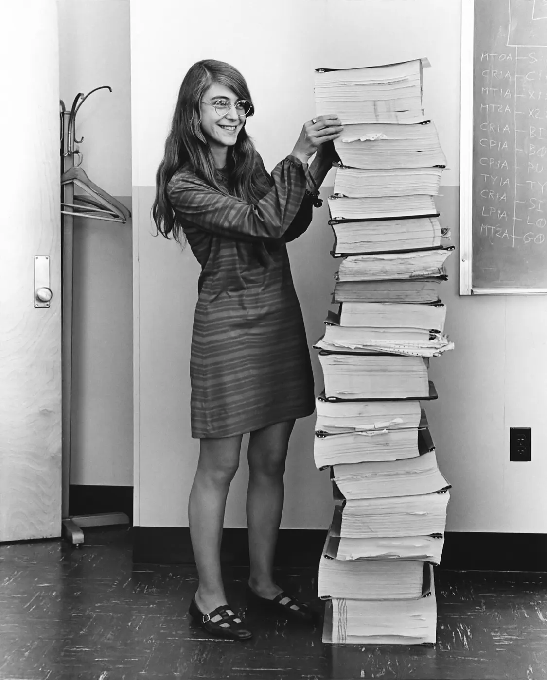 Margaret Hamilton standing beside a stack of printed Apollo guidance code as tall as she is, 1969