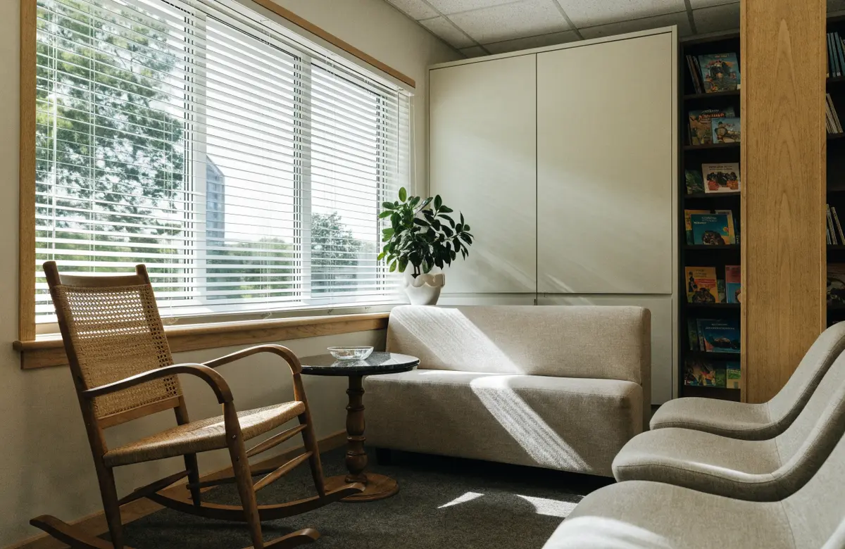 The family waiting area with books, a rocking chair and a big window