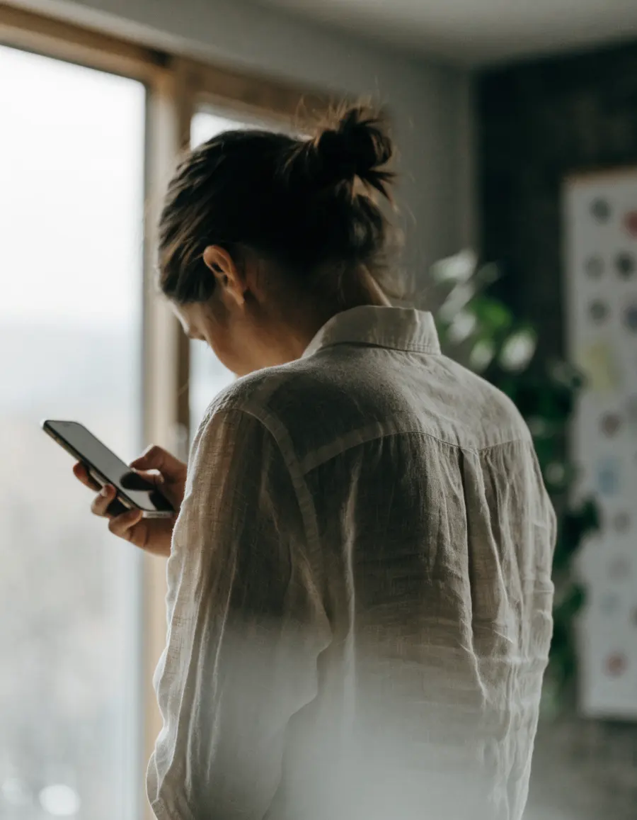 An agency owner by a studio window reading a phone