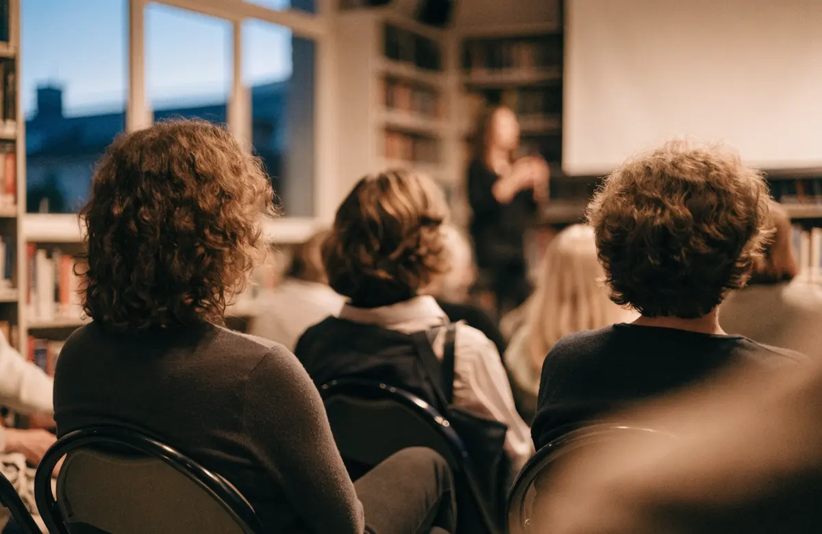 Parents seated in a school library listening to a talk, seen from behind
